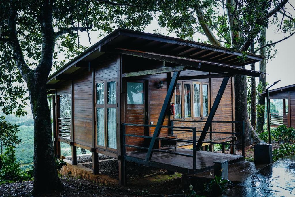 a tiny house with a porch and a tree at Stanmore Garden Bungalow in Vālpārai