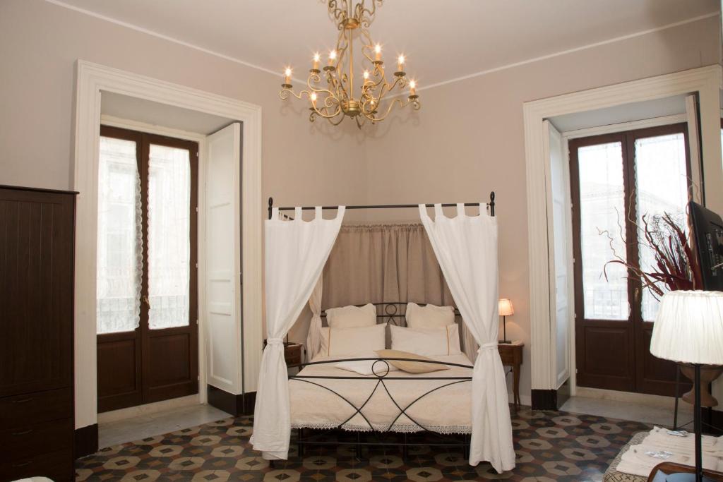 una camera con letto a baldacchino e lampadario pendente di B&B Suite Cutelli a Catania