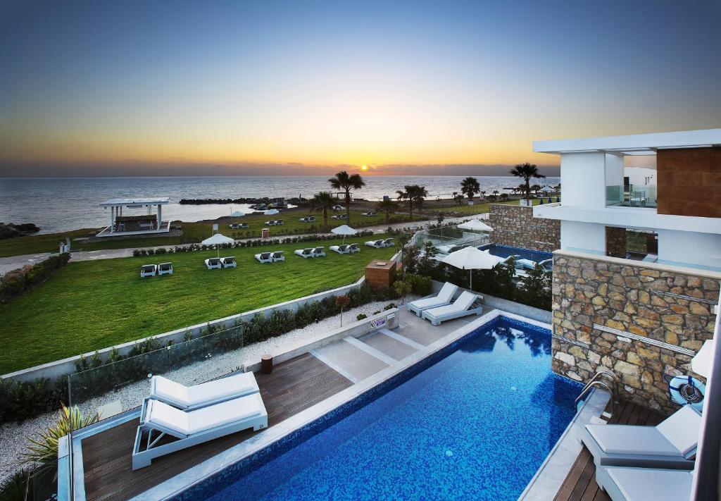 a swimming pool with a view of the ocean at Paradise Cove Luxurious Beach Villas in Paphos