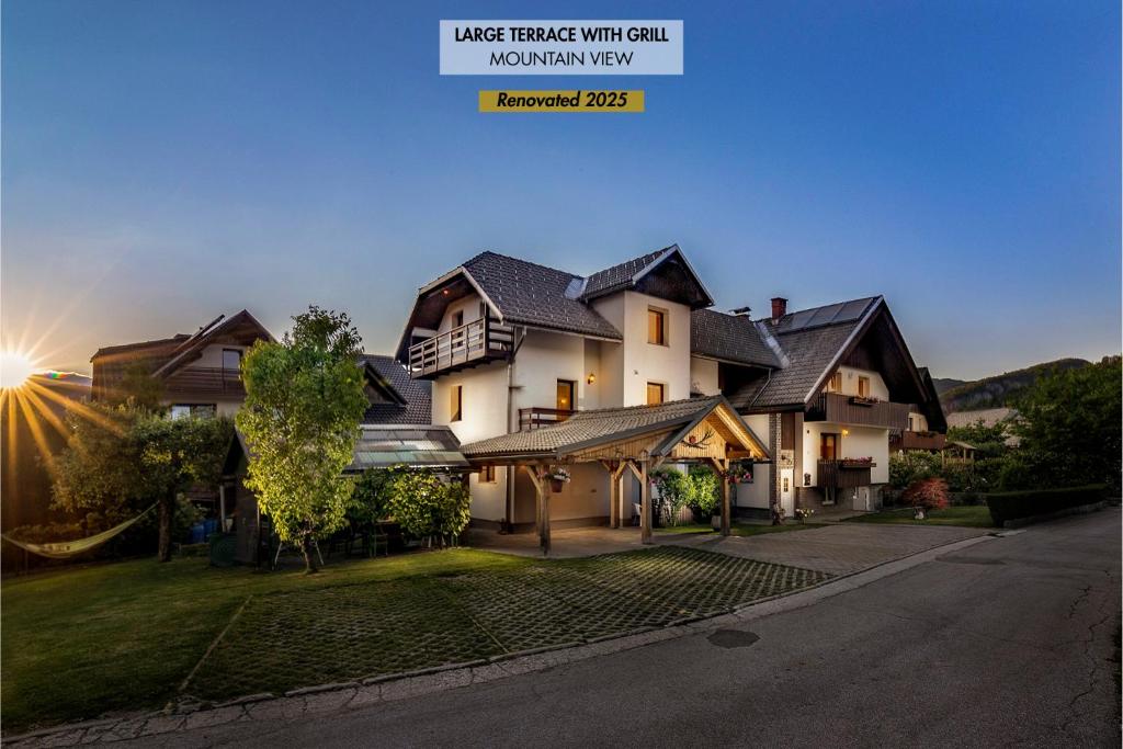 a large house with the sun setting behind it at Apartments Green Paradise in Bohinj