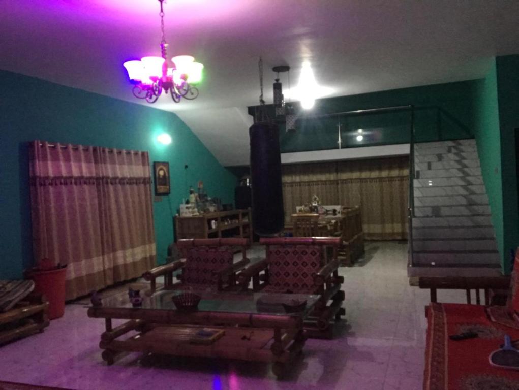 a living room with purple lights and a room with chairs at Lucky villa in Sylhet