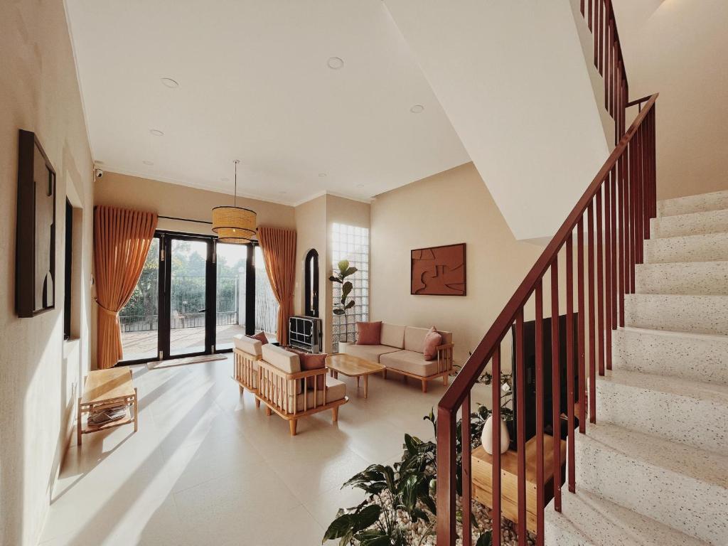 a living room with a staircase with a couch and chairs at XOM House Biển Hồ in Bien Ho