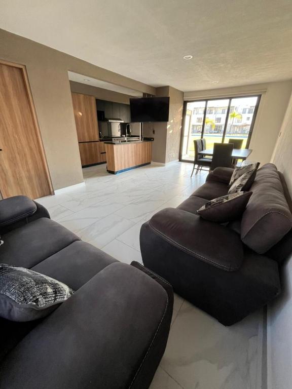 a living room with two black couches and a kitchen at Xochitepec Residencial in Atlacholoaya