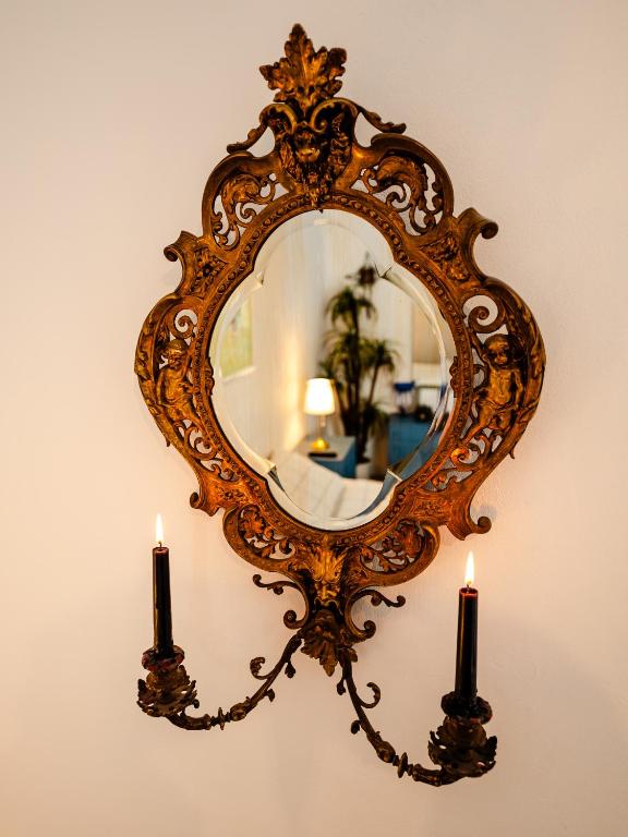 an ornate mirror with two candles on a wall at Central Art Apartment with Treasure Hunt, Free Parking & Self Check-In in Constanţa