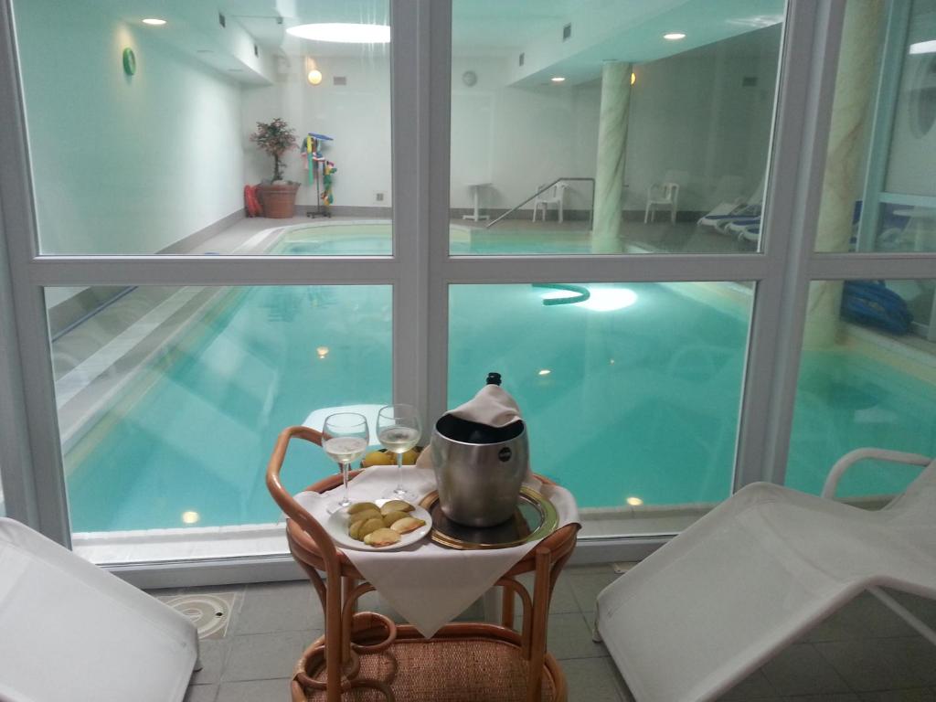 a table with a tea pot and glasses next to a pool at Hotel Olimpic in Baselga di Pinè