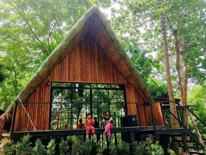 three children are sitting in front of a tree house at Campo De Laiya in San Juan