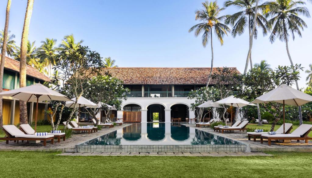 a resort with a swimming pool with chairs and umbrellas at Kayaam Wellness in Tangalle