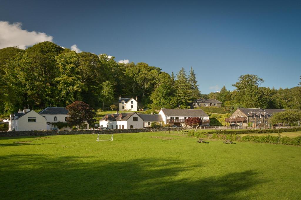 a large green field with houses in the background at Melfort Village in Oban