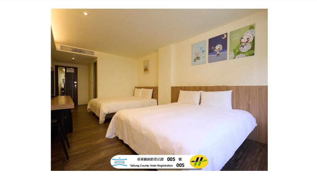 a hotel room with two beds with white sheets at Traveller Inn - Rail Haus in Taitung City