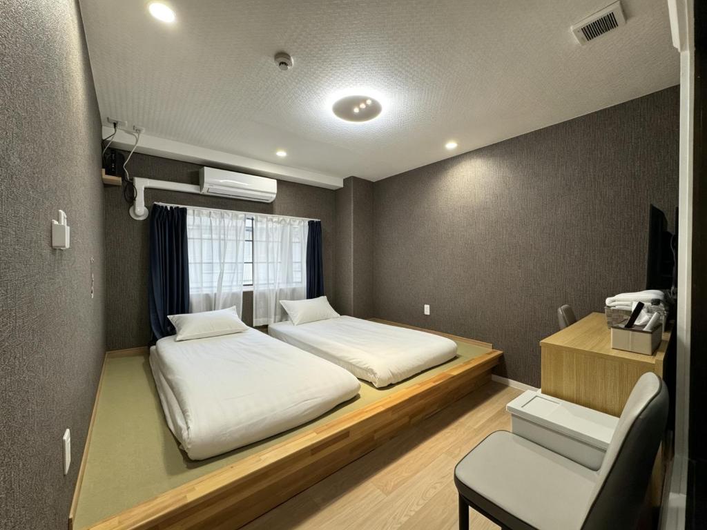 a small room with two beds and a chair at Ruka Hotel Tennoji in Osaka