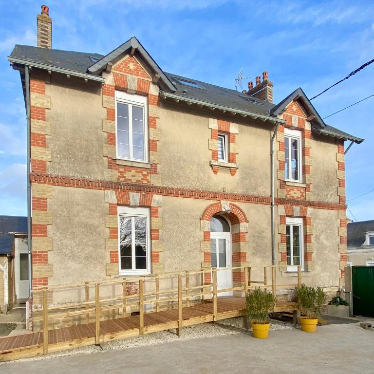 a brick house with a wooden fence in front of it at Les LOTUS de BELLE-YLE in Yvré-lʼÉvêque