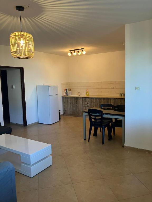 a kitchen with a table and a white refrigerator at קסם המעיינות in Bet Sheʼan