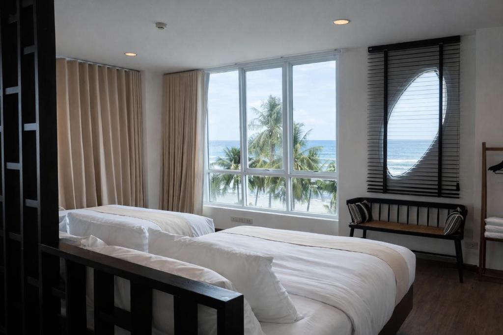 two beds in a room with a large window at The Beach Bangsaen by Thanthita next to Wonnapa beach FREE DISNEY PLUS in Bangsaen