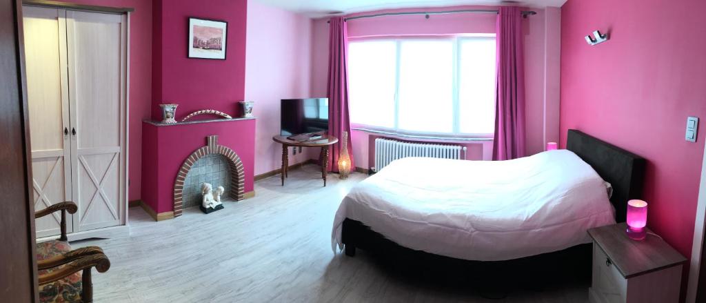 a pink bedroom with a bed and a fireplace at Bella Noche Brugge in Bruges