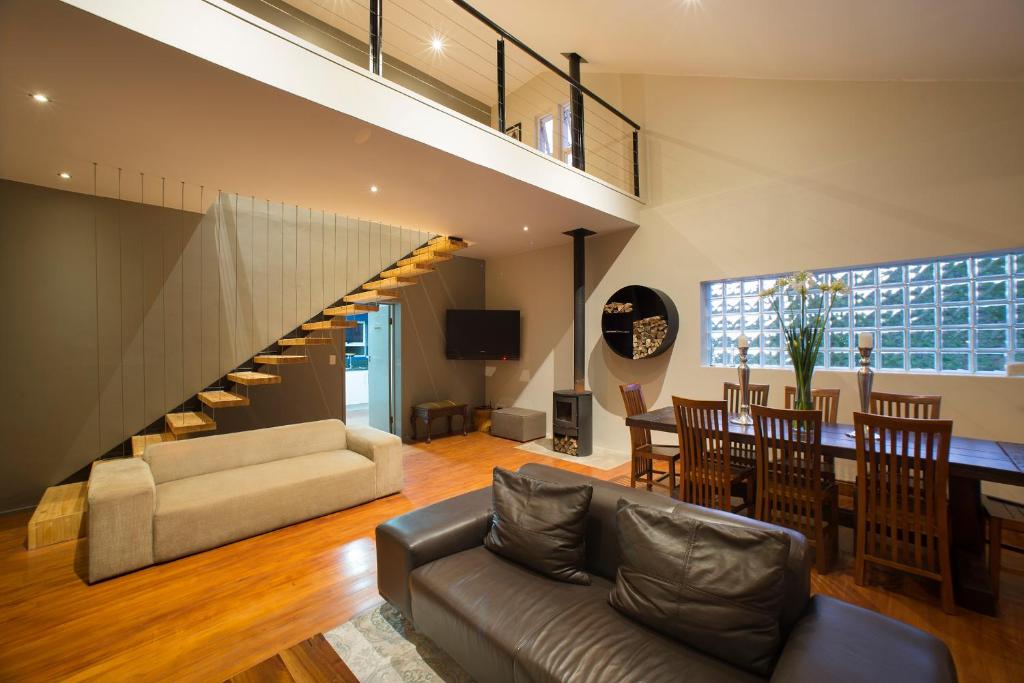 a living room with a staircase and a dining room at Tides End Manor House in Knysna