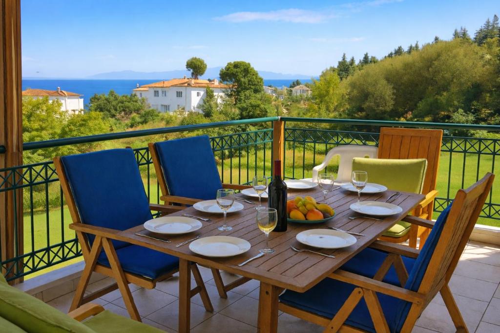 a wooden table with chairs and a bottle of wine on a balcony at E&M Villa Sea View in Polychrono