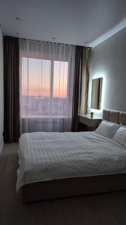 a bedroom with a bed and a large window at Umayahouses ЖК Орбита in Karagandy