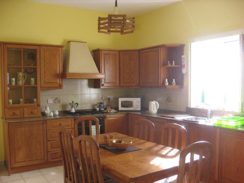 cocina con armarios de madera y mesa de madera en Valletta Gateway Maisonette en La Valeta