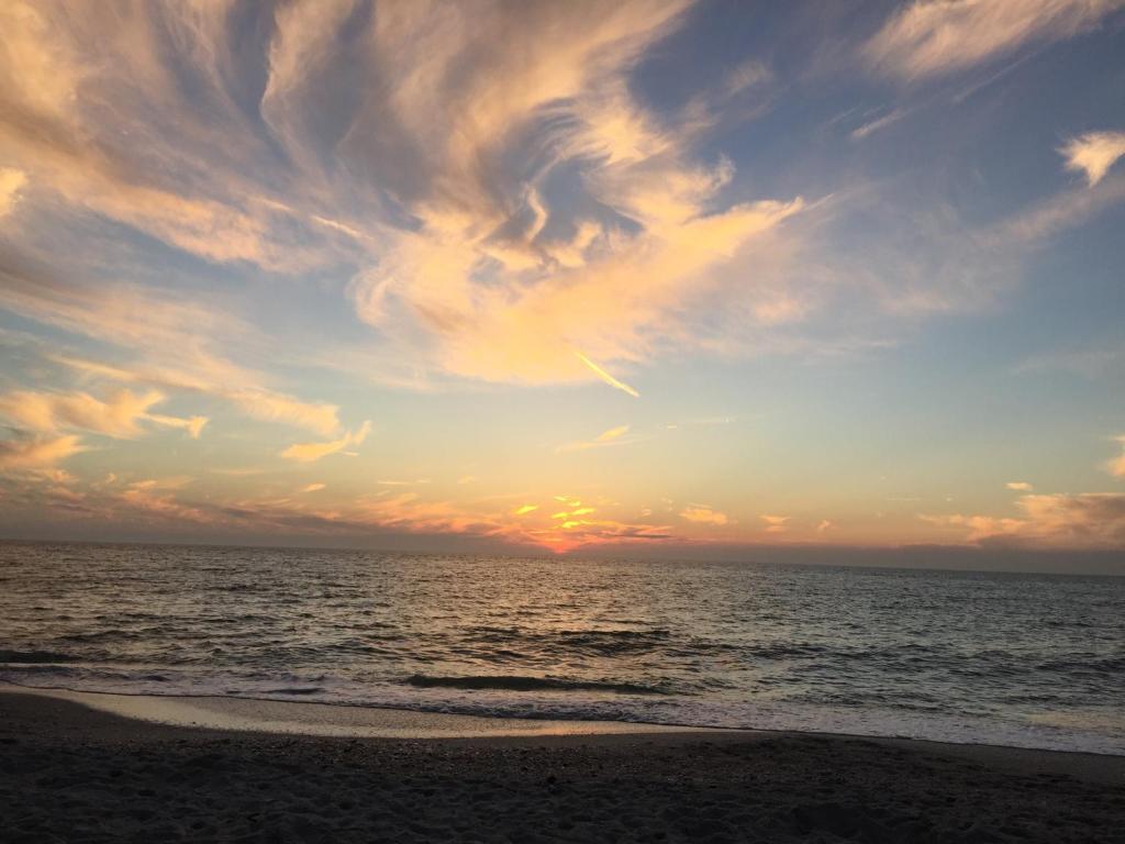 a sunset over the ocean with a cloudy sky at Home by Beach 5 - The Treehouse in Naples
