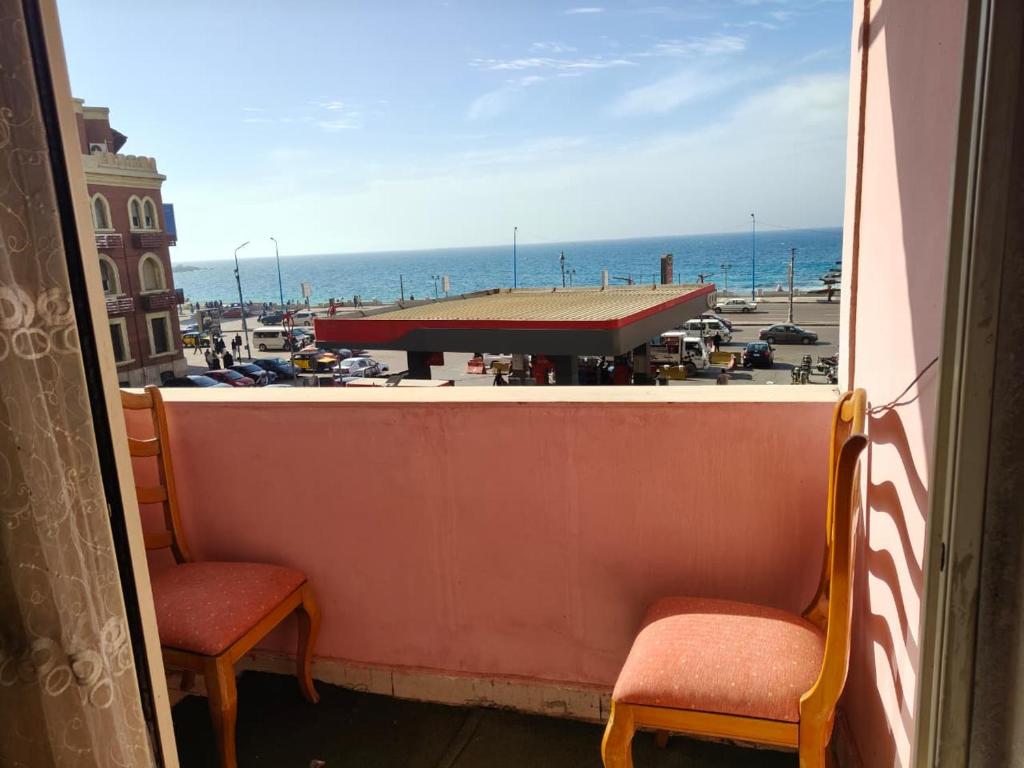 a balcony with two chairs and a view of a parking lot at luxurious direct seaview apartment in Alexandria