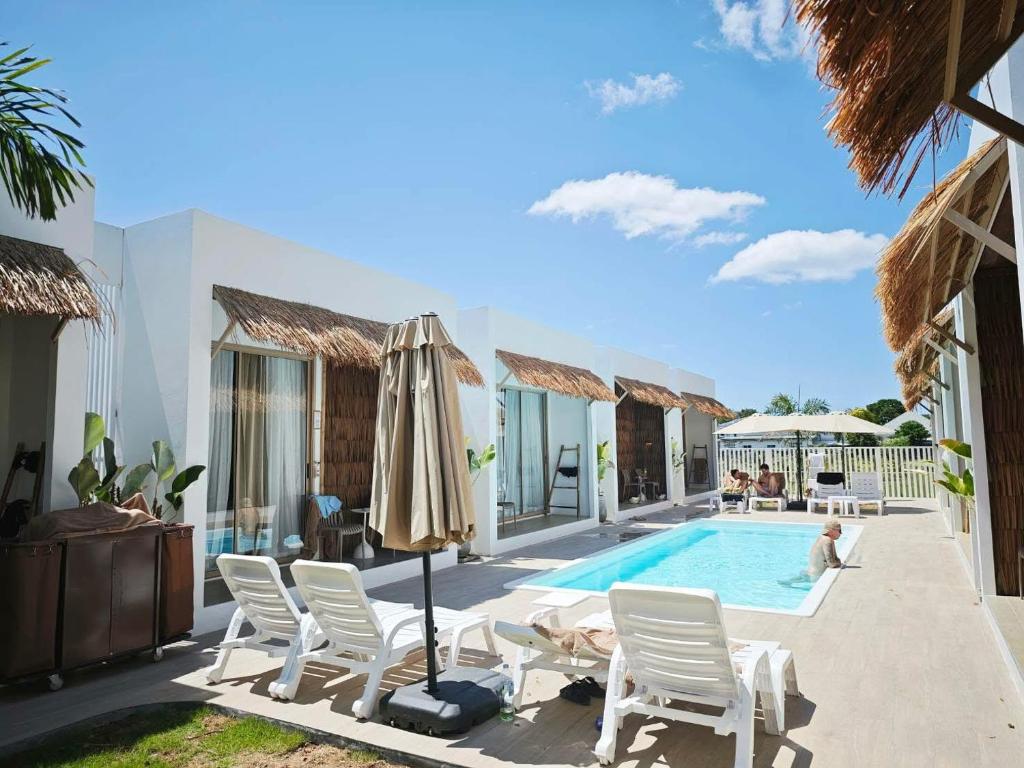 a villa with a swimming pool with chairs and an umbrella at The Pool House Koh Lanta in Ko Lanta