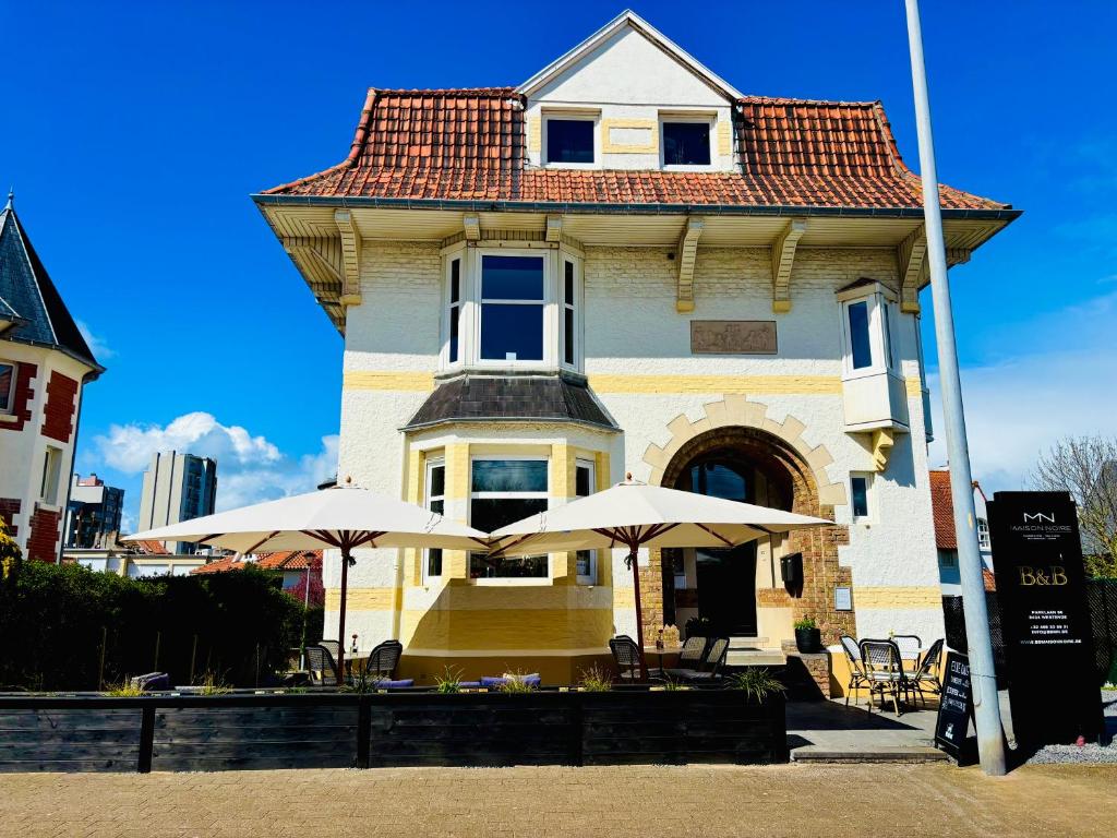 a house with two umbrellas in front of it at Bed & Breakfast Maison Noire Westende-bad incl parking & ontbijt in Middelkerke