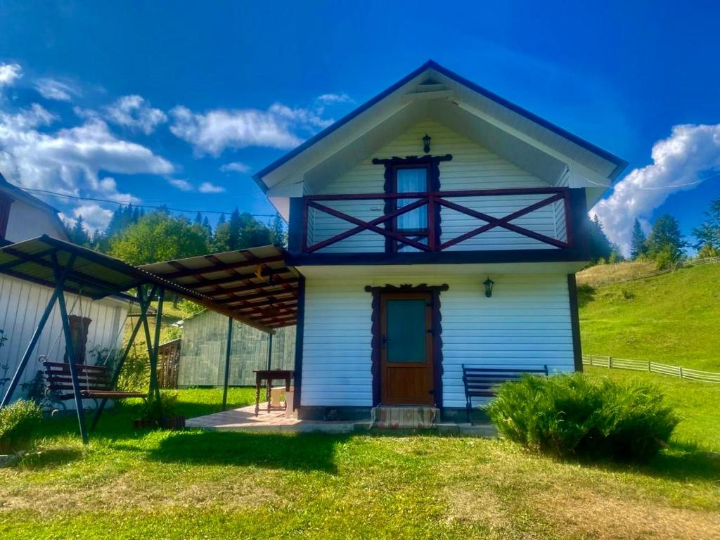 a small white house with a red door at Дідова Хата in Shibeny