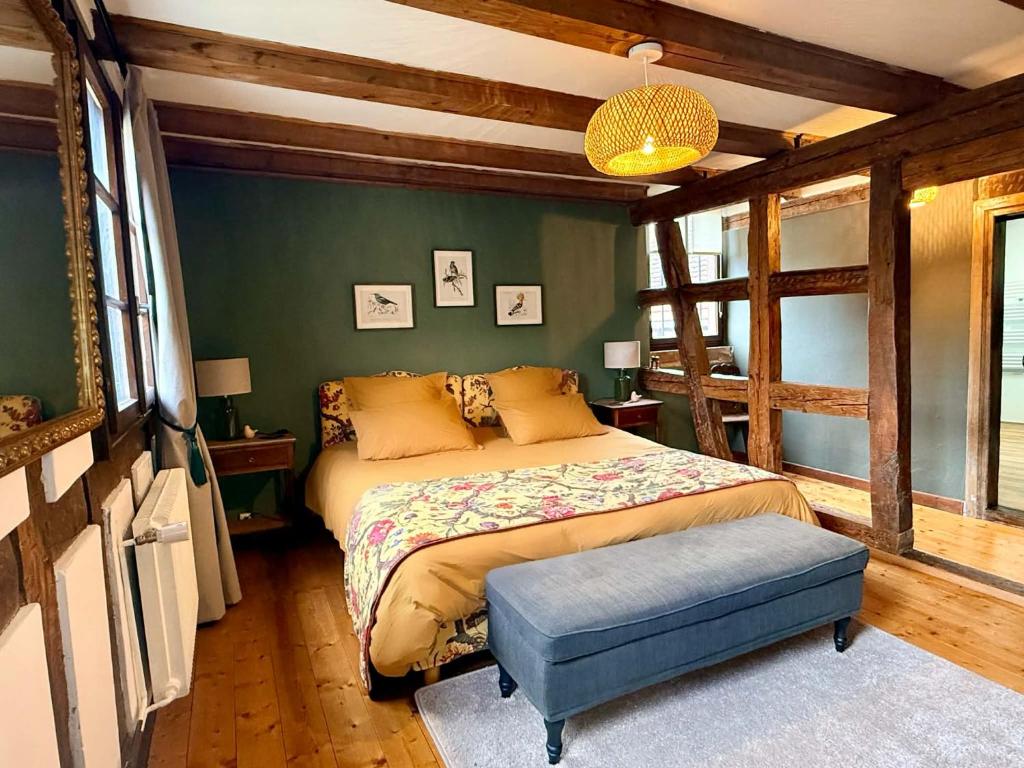 a bedroom with a bed and a blue ottoman at L'Héritage 1779 in Duntzenheim