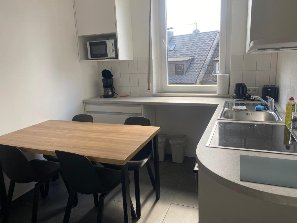a kitchen with a wooden table and a sink at Stefans Apartments B - 20 min bis DD Messe und Flughafen inkl Parkplatz in Willich
