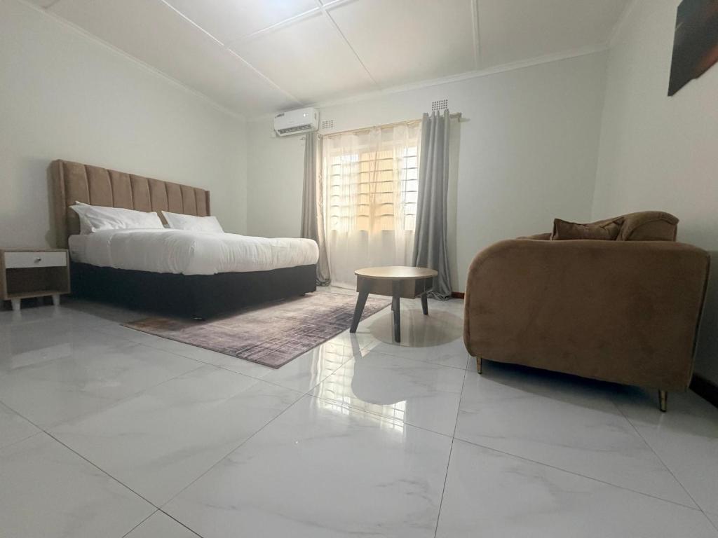 a bedroom with a bed and a couch and a chair at Destiny Executive Apartments in Solwezi