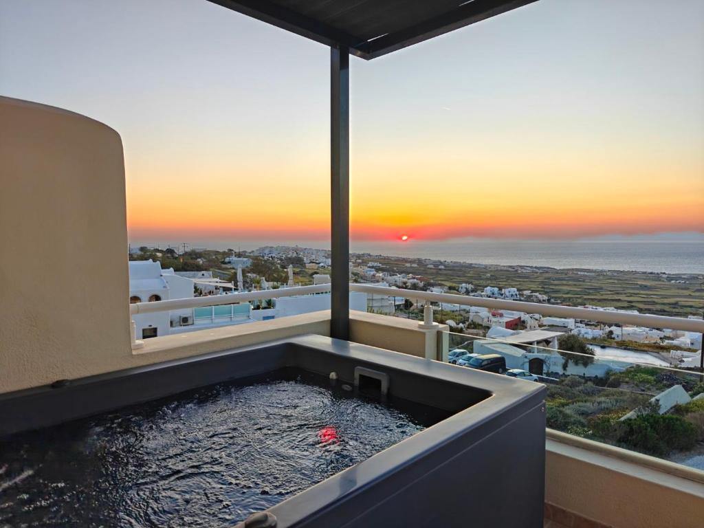 a bath tub with a sunset in the background at Kiklamino Sunset Suites in Oia