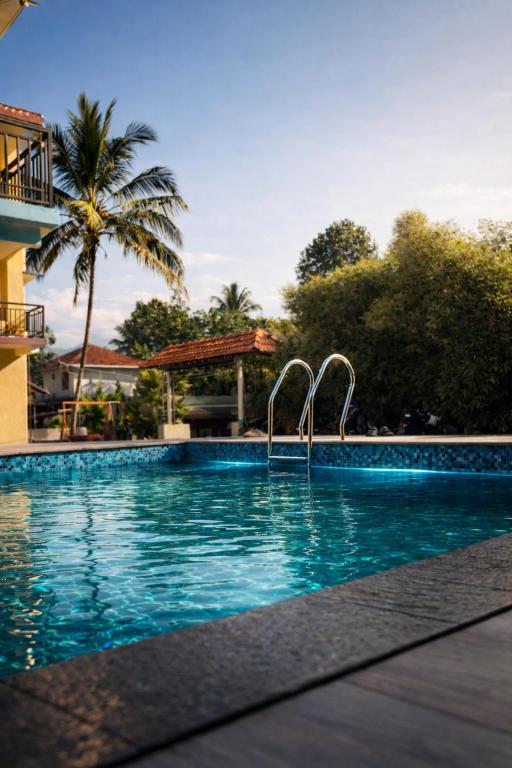a swimming pool at a resort with a palm tree at Rivera Holidays in Vythiri