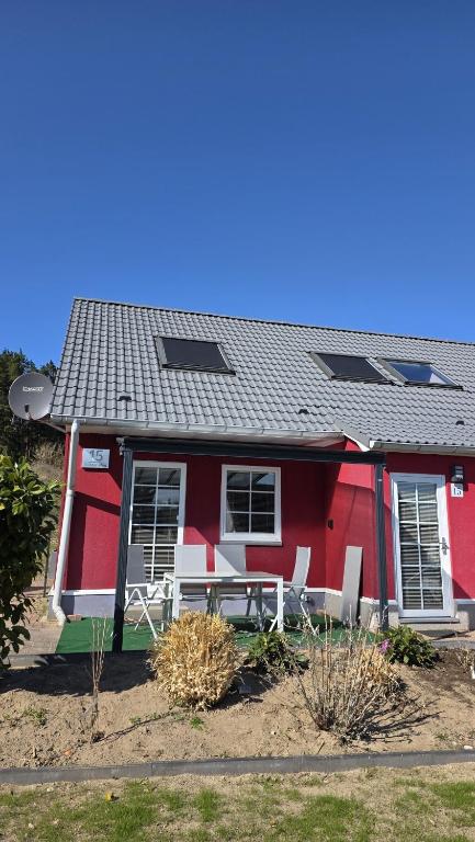 a red house with a table and chairs in front of it at Schwedenhaus, Am Achterwasser, Urlaub mit Hund in Lütow