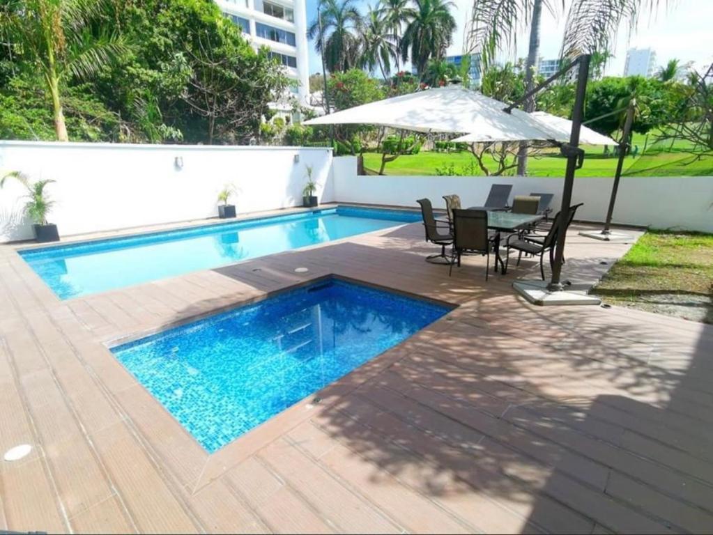 a swimming pool with a table and chairs and an umbrella at Suite Club Deportivo in Acapulco