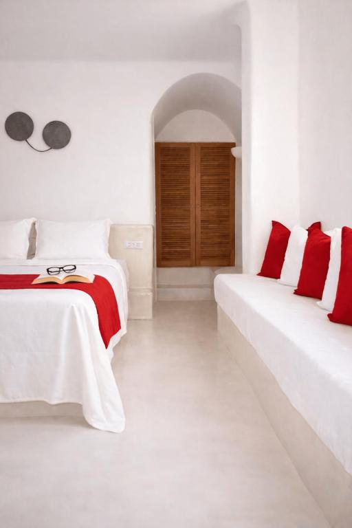 two beds in a white room with red accents at Finikia Memories Hotel in Oia