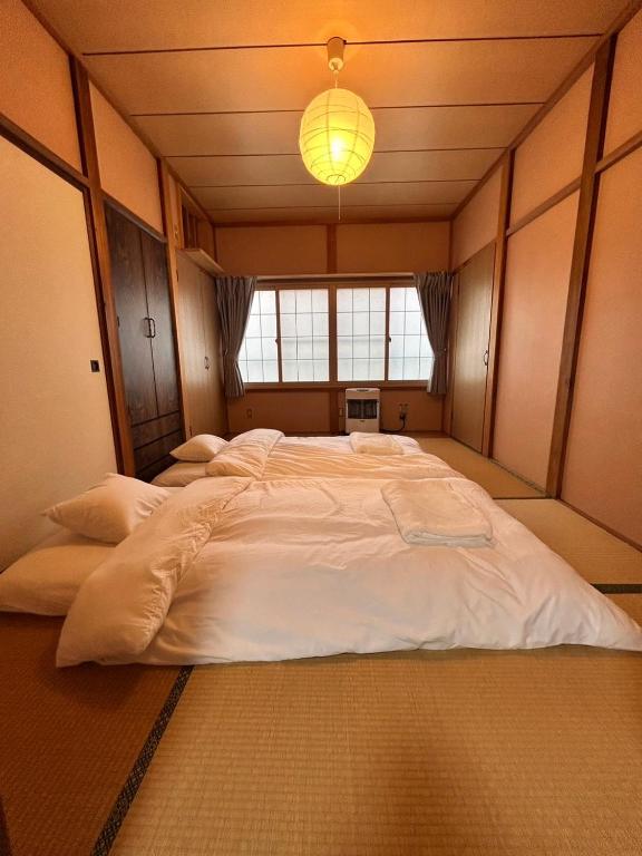 a large white bed in a room with a window at AOMORI LOVERS Minatomachi Base in Aomori