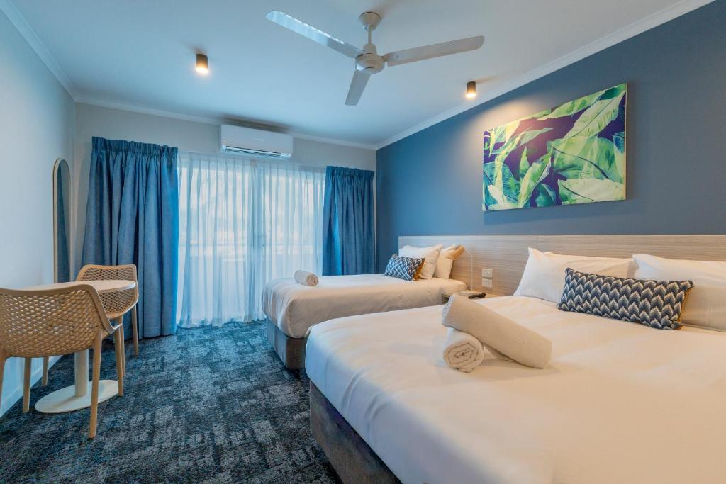 a hotel room with two beds and a couch at Cairns Southgate Hotel in Cairns