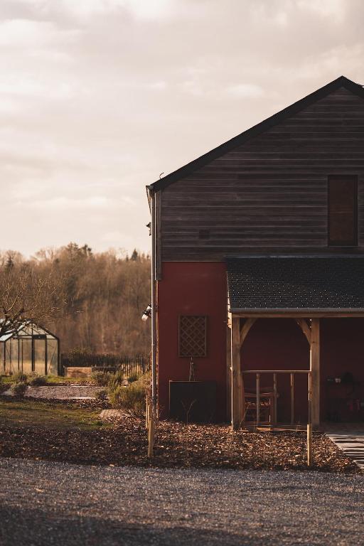 a red barn with a black roof at La Maison des Champs in Ciney