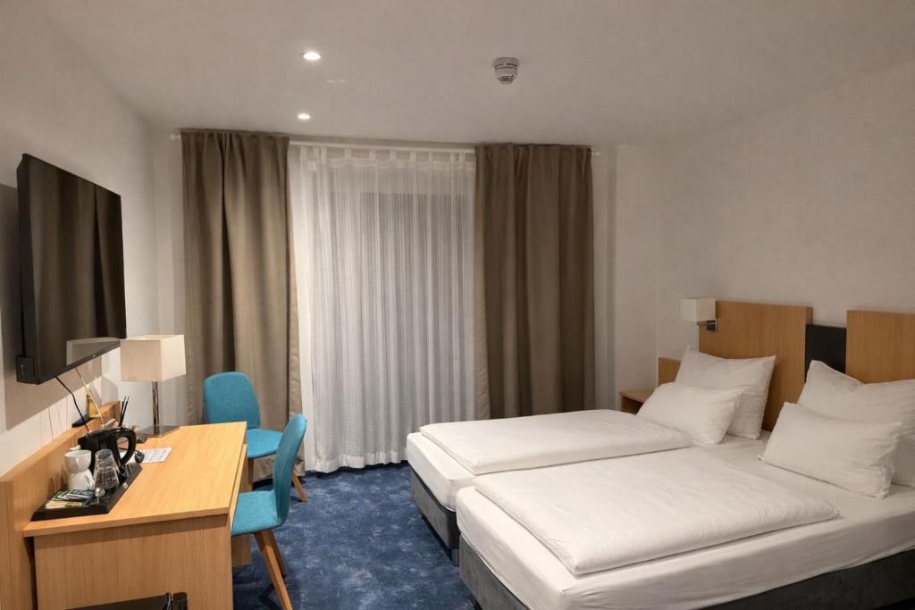a hotel room with two beds and a desk at HELENA Hotel & Restaurant in Mirow