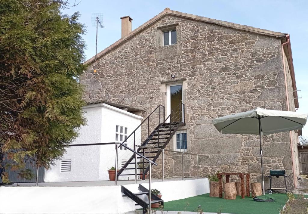 a stone building with a staircase and an umbrella at Brisa do Mar in Laxe