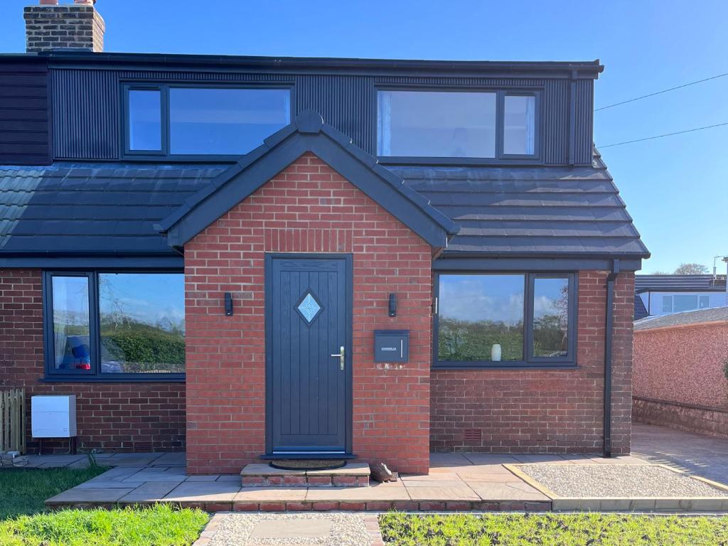 a red brick house with a black door at Wardenlea in Preston
