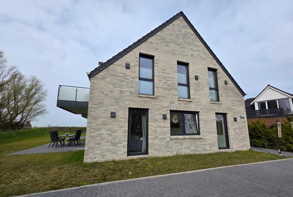a brick house with a deck on the side of it at Ferienwohnung Möwentöne in Bensersiel