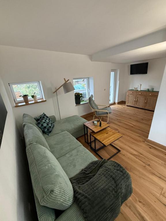 a living room with a green couch and a table at Ferienwohnung Waidmannsheil in Amtsberg