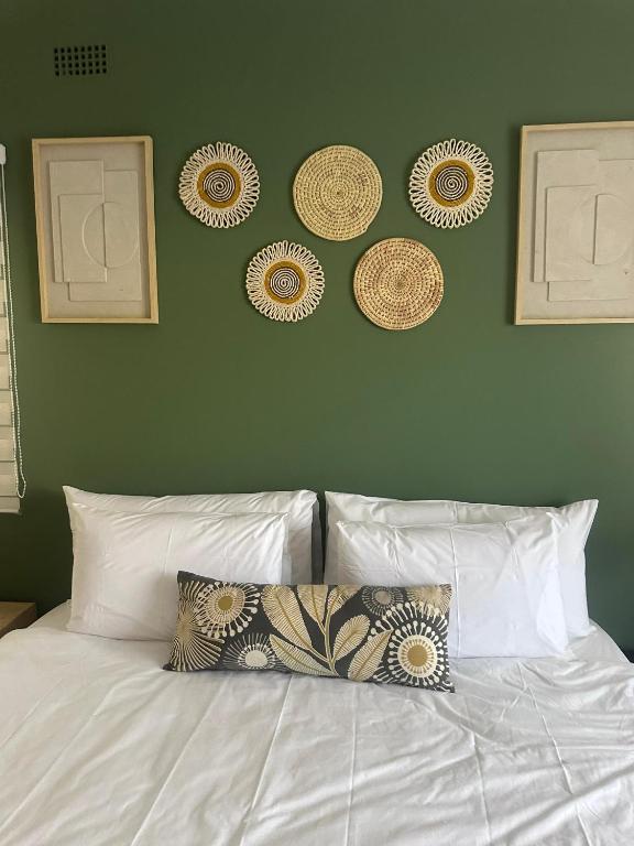 a bed with a green wall with plates on it at Imbarudo Residence in Victoria Falls