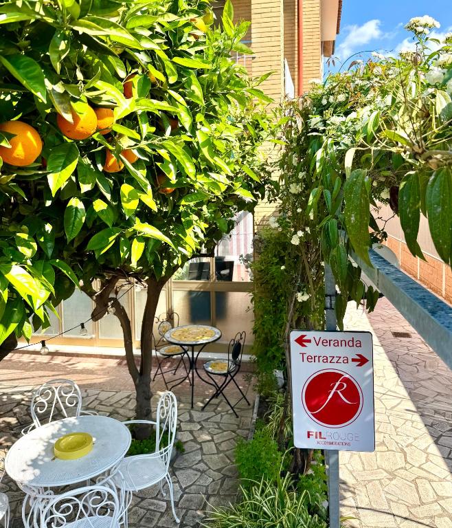 a sign in front of an orange tree with a table and chairs at Fil Rouge in Ciampino