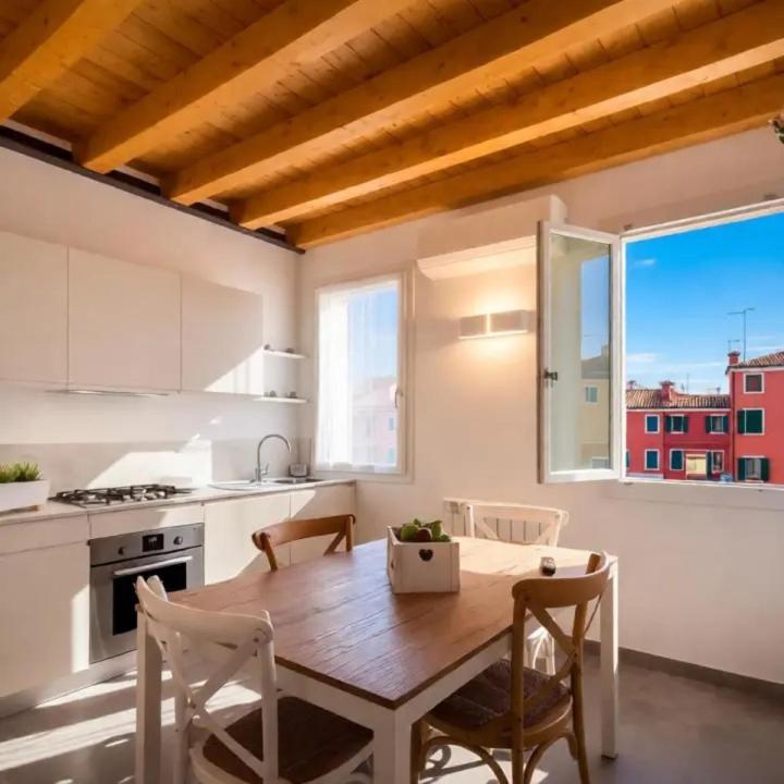 a kitchen with a wooden table and chairs in a kitchen at Suite Laguna Sunset in Chioggia