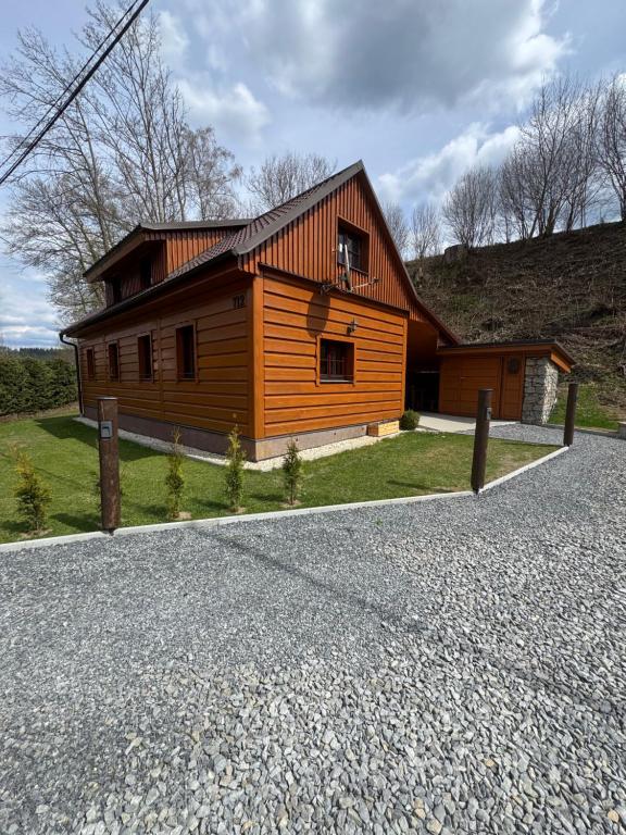 a small wooden house on a gravel road at Chalupa Nella in Velké Karlovice