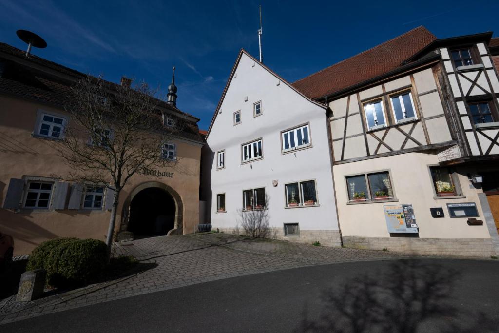 a white building with an archway next to two buildings at Gästehaus Willanzheim in Willanzheim