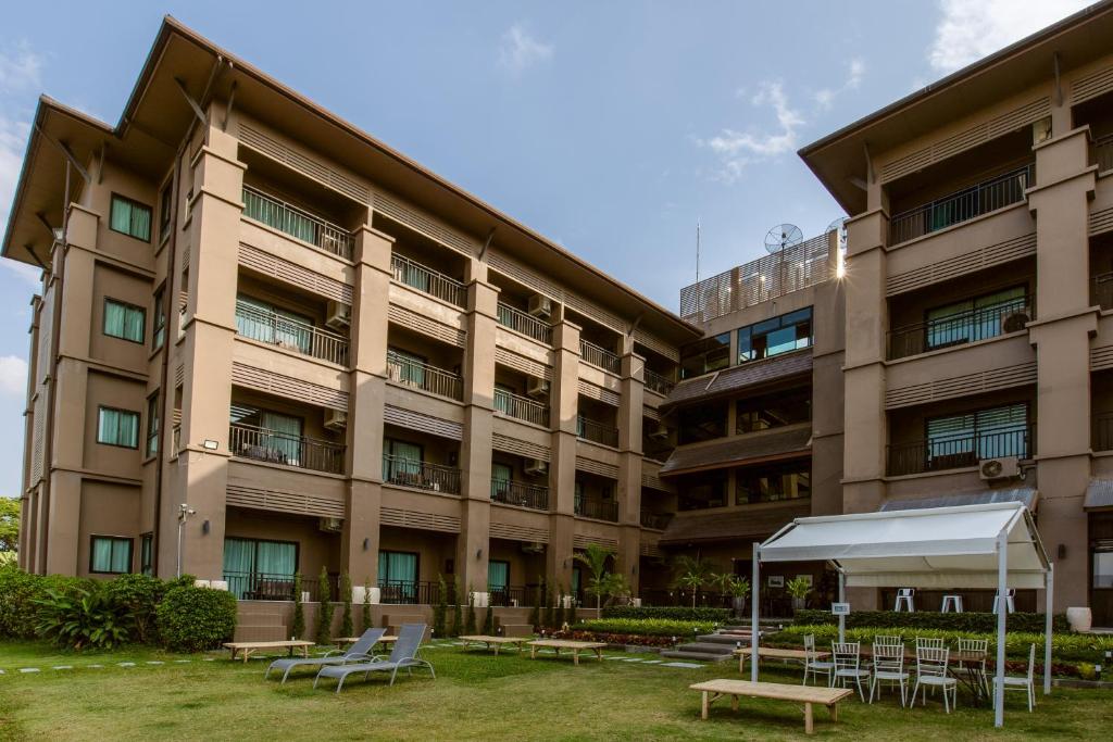 a large building with tables and chairs in front of it at Brown House Hotel in Udon Thani