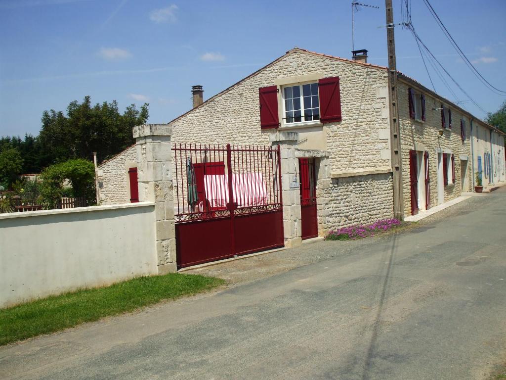 a brick house with red doors on a street at La Piaule in Saint-Pierre-le-Vieux